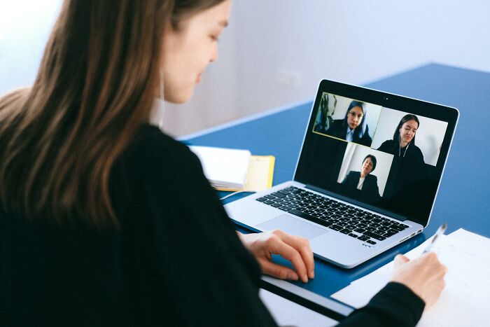 Person in a virtual job interview, noting tips on identifying biggest red flags, with laptop and notebook on a desk.