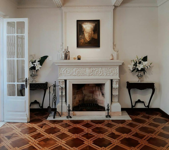 Elegant room with ornate fireplace and eerie portrait, evoking creepy ambiance.