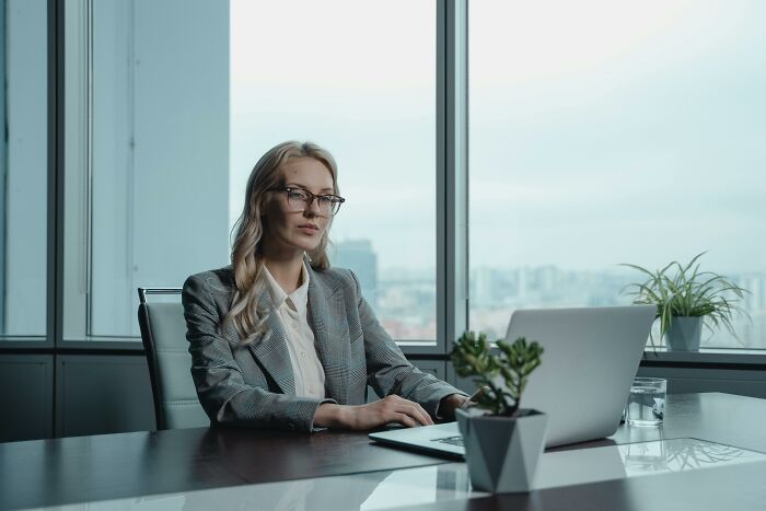 Person in an office, wearing glasses and a gray suit, sitting at a desk using a laptop, symbolizing biggest red flag job interview.