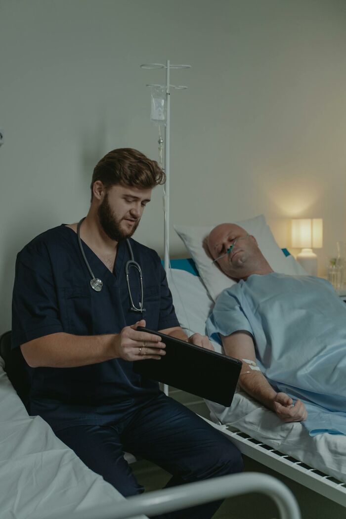 Doctor reviewing notes beside a patient in a hospital, illustrating medical experiences.