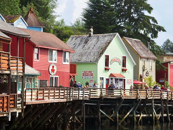 Colorful waterfront buildings, vibrant scene, people strolling, capturing the essence of quaint town life with absolute confidence.