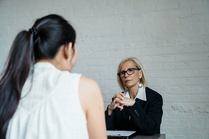 Job interview scene with interviewer in glasses observing candidate.