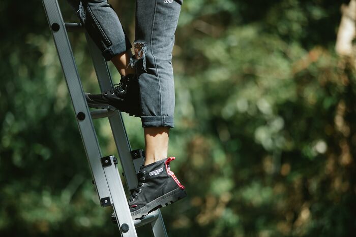 Person climbing a ladder in distressed jeans and sneakers, illustrating hidden dangers of everyday activities.