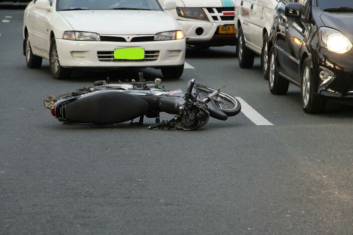 Motorcycle lying on road after accident surrounded by cars, related to first responders sharing memorable emergency calls.
