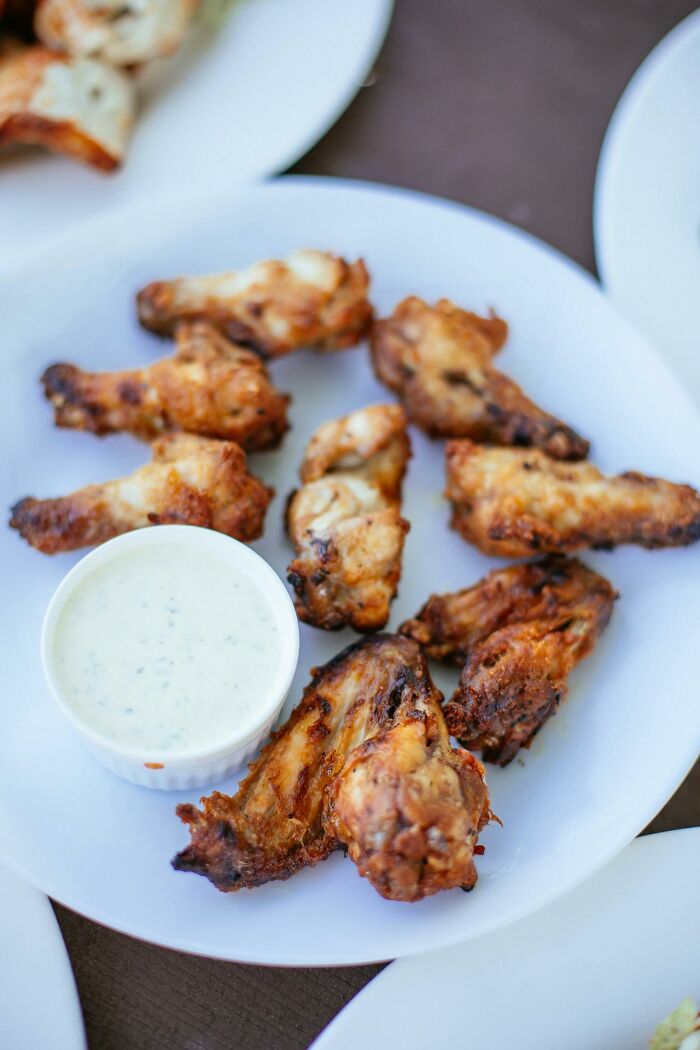 Plate of crispy chicken wings with dipping sauce on the side, photographed in a home setting.