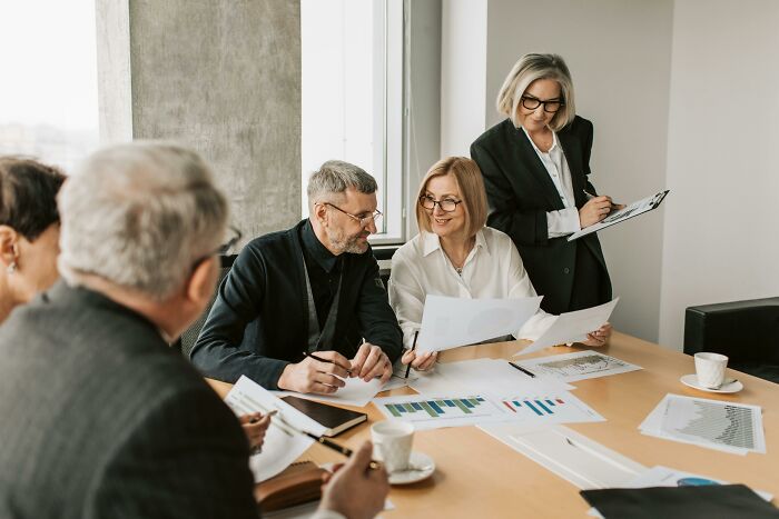 People in business attire discussing documents, highlighting biggest job interview red flags around a table in an office.