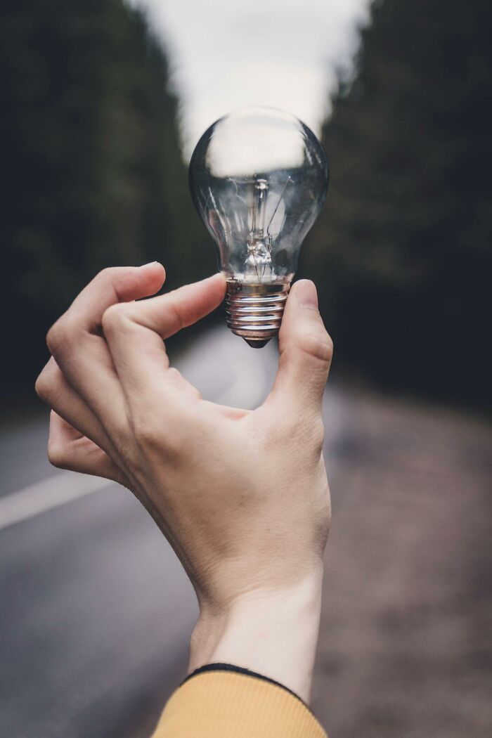 Hand holding a light bulb against a blurred outdoor background, related to disturbing findings.