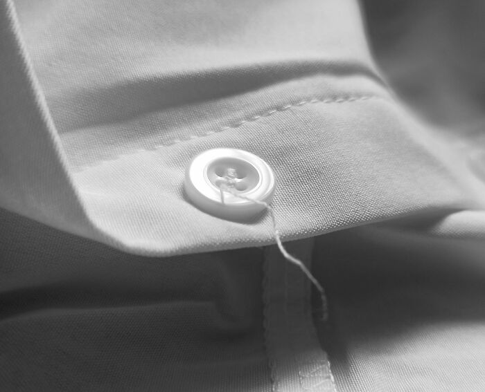 Close-up of a shirt button with visible thread, highlighting detail often unnoticed by guys before having a girlfriend.