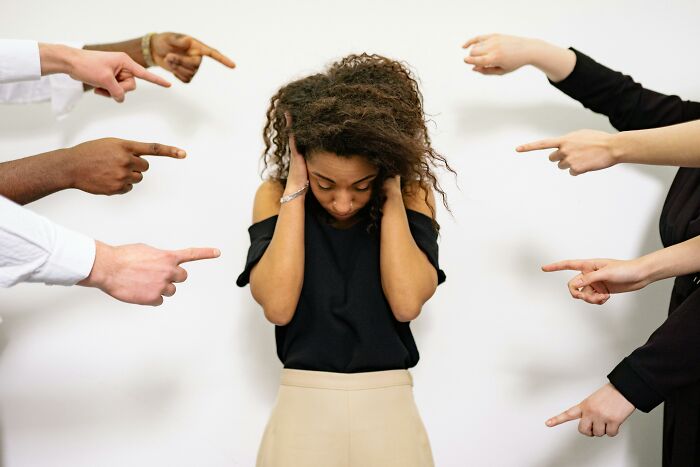 Woman overwhelmed and covering ears as multiple hands point at her depicting ghastly things told in church causing people to quit going