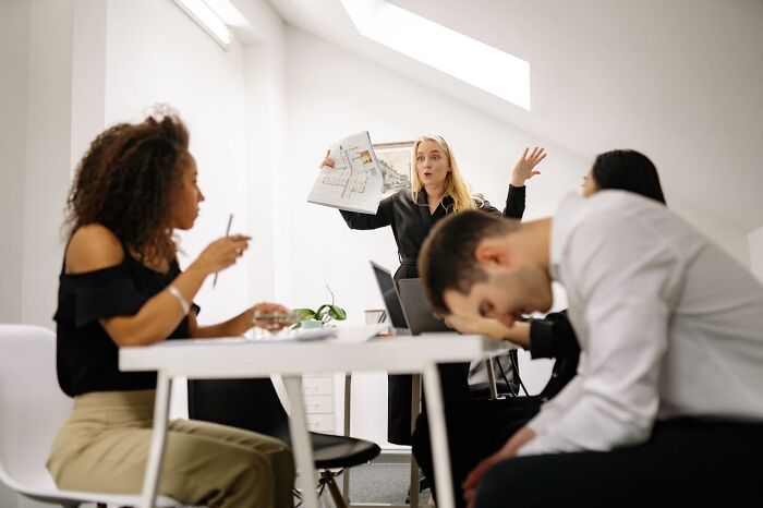 Office meeting scene with a stressed woman holding papers, capturing something more traumatizing than people realize.