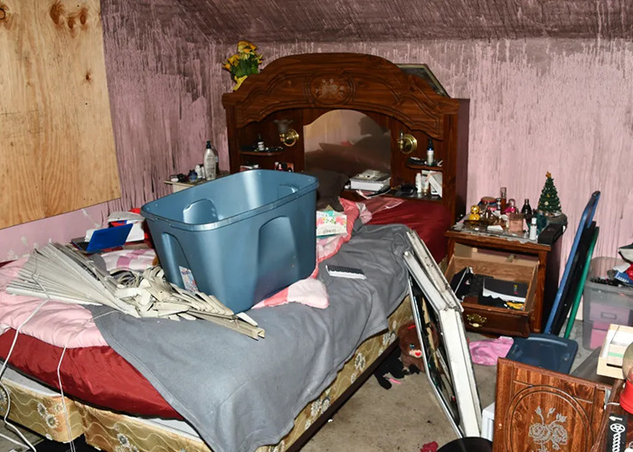Cluttered horror house bedroom with broken furniture and neglected items.