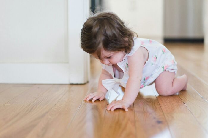 A baby crawling on hardwood floor, exploring with curiosity.