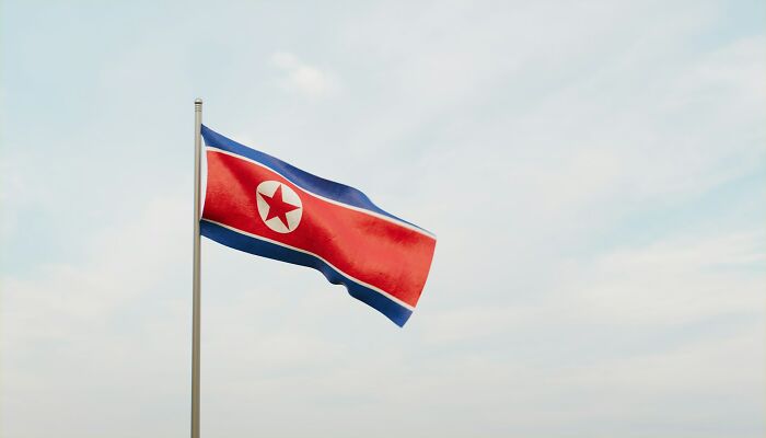 North Korean flag waving under a clear sky, potential danger awareness.
