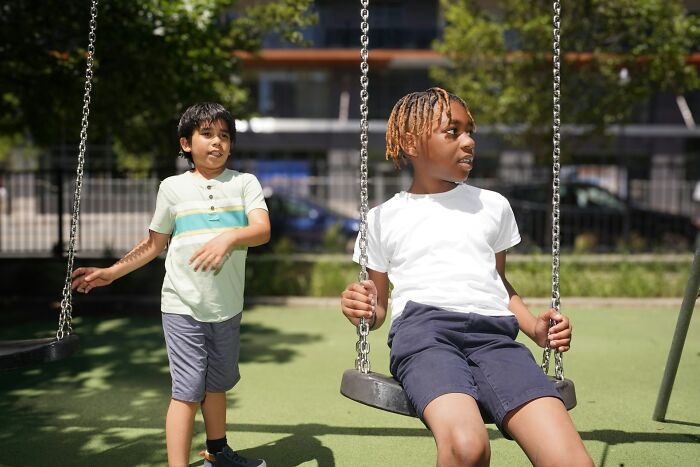 Children playing on swings in a sunny park.