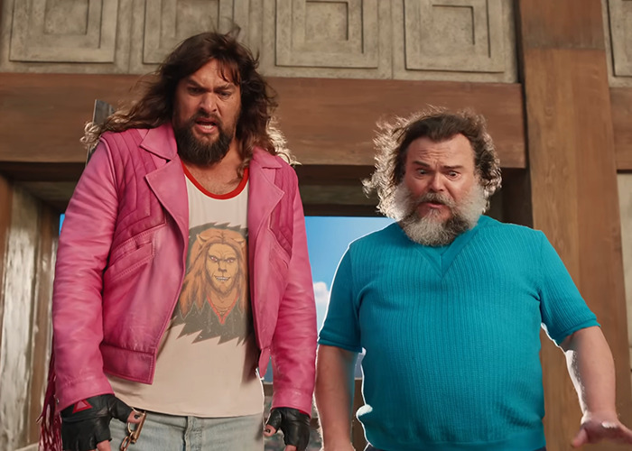 Two men in colorful attire stand indoors, reacting to a scene, related to TikTok trend disrupting 'Minecraft Movie' screening. Two men in colorful attire stand indoors, reacting to a scene, related to TikTok trend disrupting 'Minecraft Movie' screening.