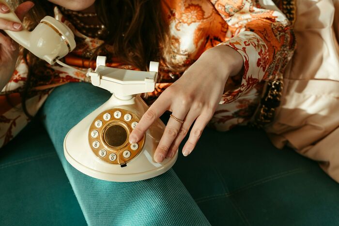 A person using a vintage rotary phone, capturing a nostalgic moment from 30 years ago.