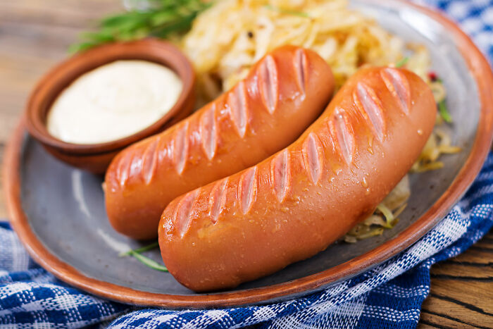 Cheddar bratwursts served on a plate, highlighting product recall due to hard plastic discovery.