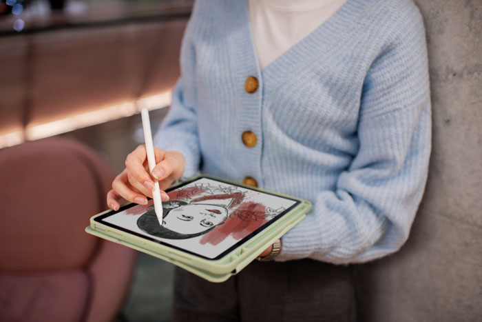Person drawing a digital portrait on a tablet, showcasing artistic skills and creativity.