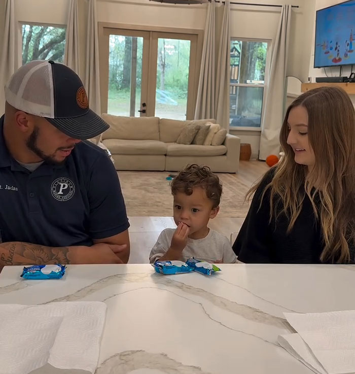 A man and woman sit with a child in between them at a kitchen counter.