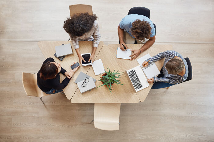 People gathered around a conference table with laptops and notebooks, illustrating ineffective productivity tips in action.