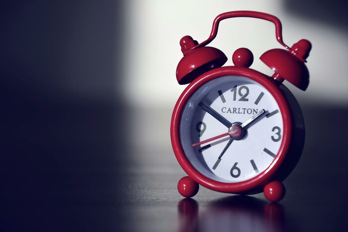 Red alarm clock on a table, symbolizing productivity tips and time management.