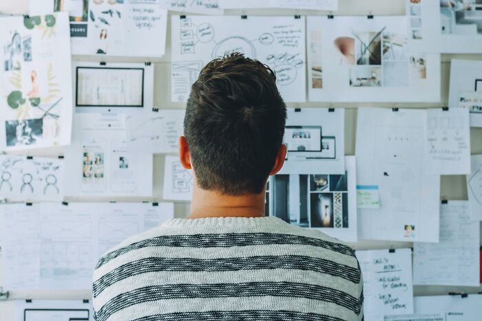 Man reviewing productivity tips on a cluttered board filled with papers and diagrams.