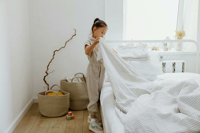 Child tidying a bed, focusing on organizing as part of productivity tips.