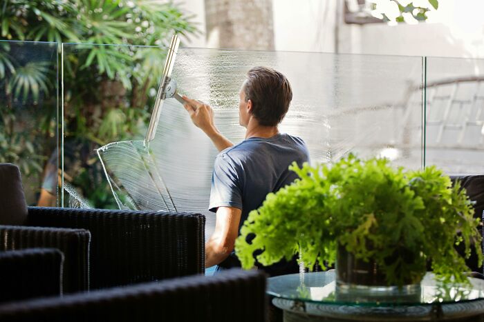 Person cleaning glass, illustrating a productivity tip in a lush outdoor setting.