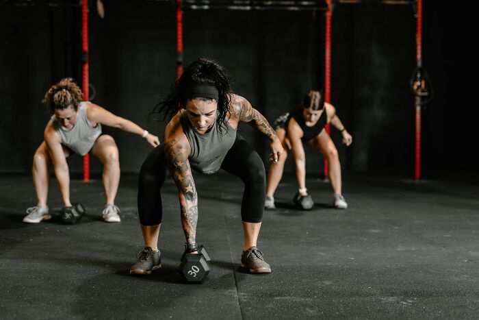 People exercising with dumbbells in a gym, focusing on quality of life improvement through fitness.