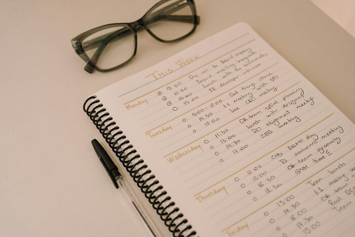 Weekly planner with pen and glasses, enhancing quality of life improvement through organized scheduling.