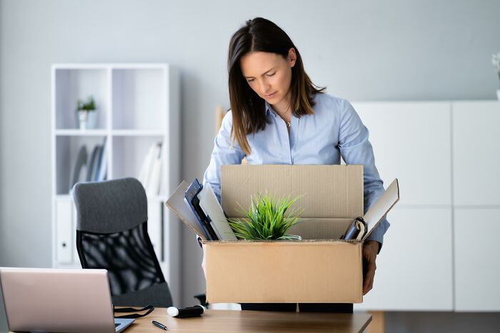 Woman packing office items in a box for quality life improvement.