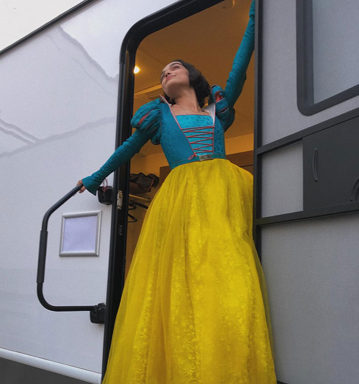 Individual in a costume standing in a trailer doorway, posing thoughtfully.