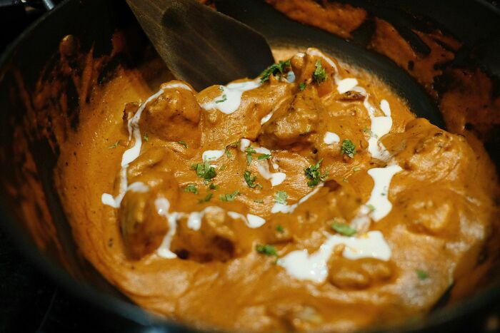 Chicken curry with creamy sauce and herbs in a pan, showcasing a top dish from different countries.