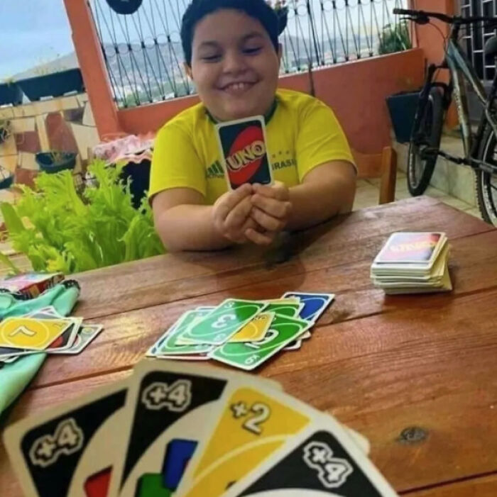 Smiling child holding UNO card during game, playful moment captured for Instagram.