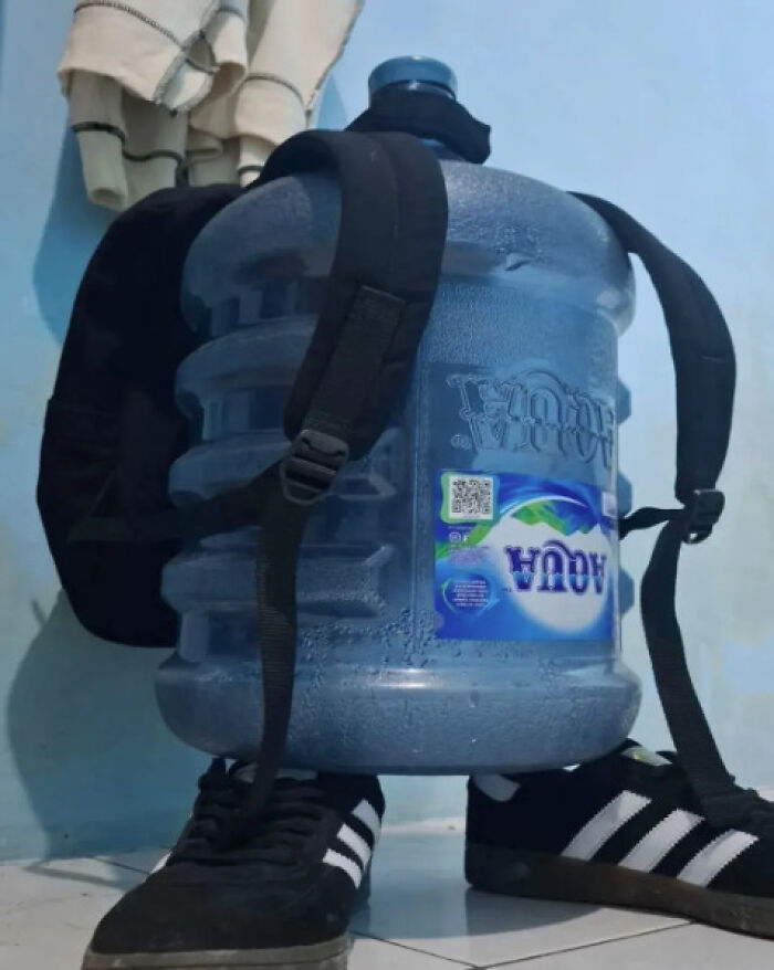 Funny image of a large water jug with straps, positioned like a backpack, with shoes underneath.