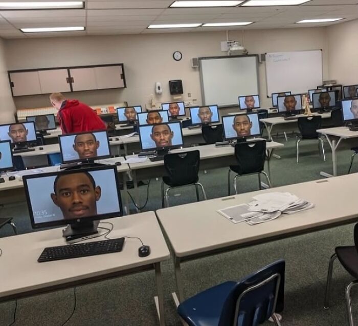 Classroom of computers displaying the same face on screens, showcasing a humorous random image.