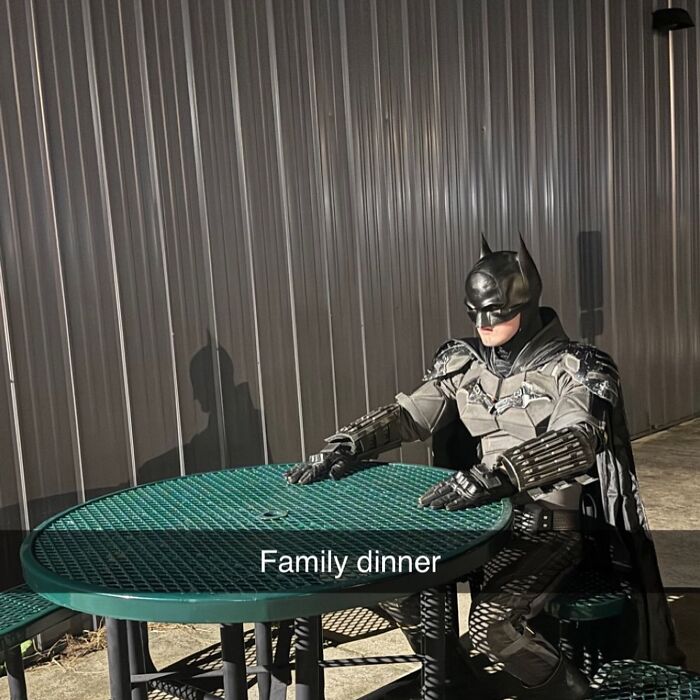 Batman sitting alone at a green picnic table, humorously captioned "Family dinner"; part of funny random images.