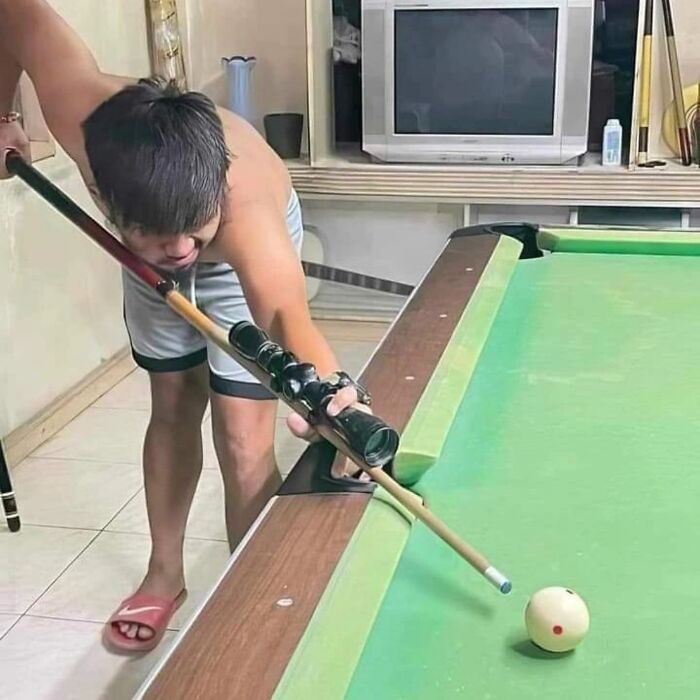 Man humorously holding multiple pool cues to hit a ball on a pool table, one of many funny images shared on Instagram.