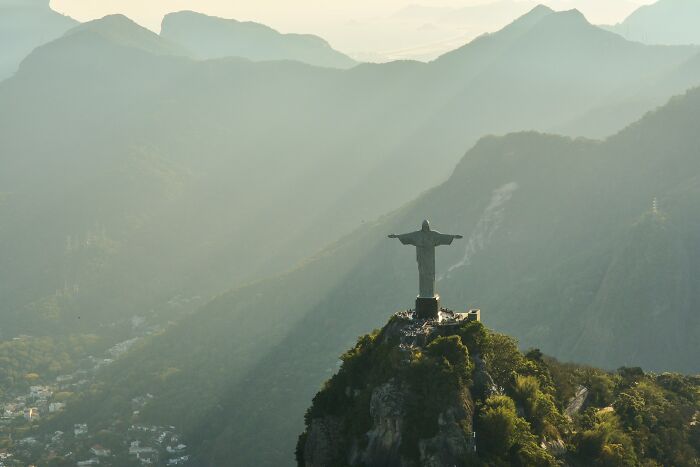 Christ the Redeemer at sunrise with misty mountains, highlighting a place not as desirable to live for the filthy rich.