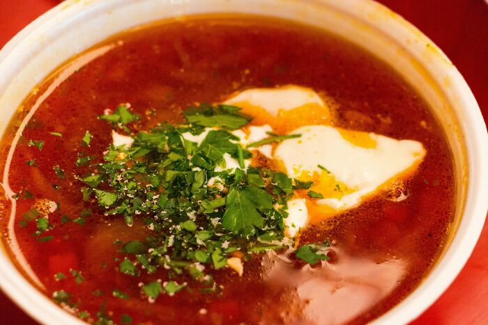 A bowl of soup topped with sour cream and herbs, representing a top dish from different countries.