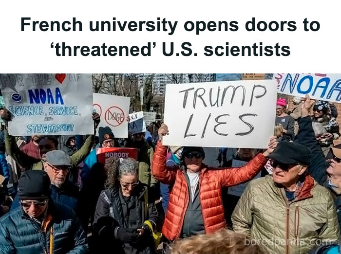 Protesters holding signs in a demonstration, including one reading "Trump Lies."