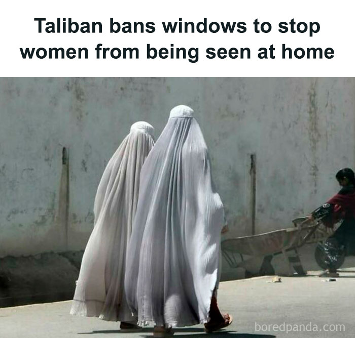 Two women in burqas walk by a wall; possible focus on fake news topic.