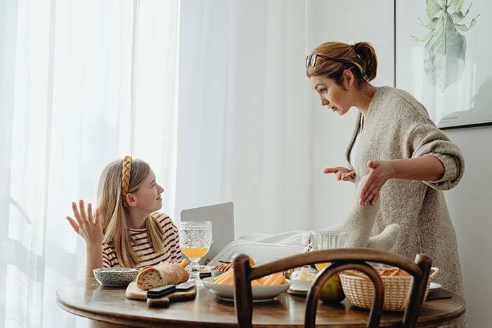 Mother giving hard truths to entitled teen at dining table.
