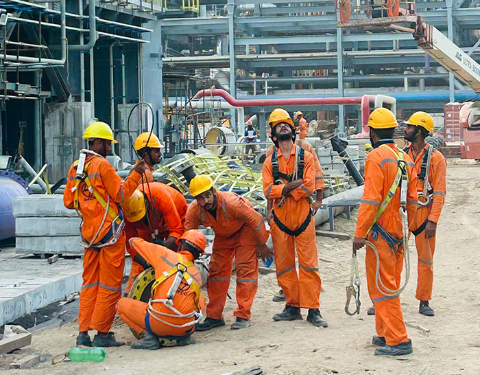 Workers in orange uniforms and helmets collaborating on a construction site, illustrating recession impacts on labor.