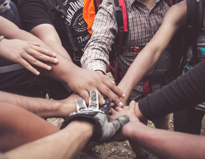 Hands of diverse people coming together in support during a recession, showcasing unity and resilience.