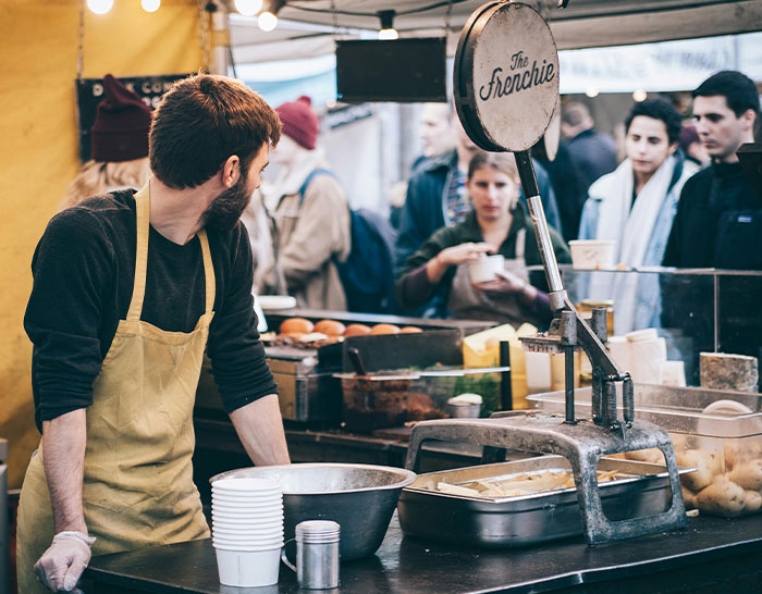 Market vendor looking at customers during a recession, highlighting economic realities.