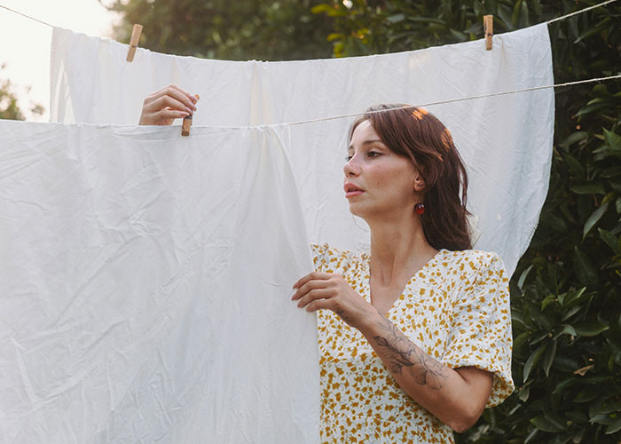 Woman hanging laundry outdoors, teaching a lesson about responsibility. Woman hanging laundry outdoors, teaching a lesson about responsibility.