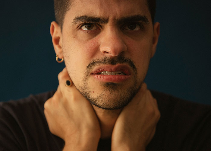 A man with a frustrated expression, hands around his neck, symbolizing a lazy man's struggle. A man with a frustrated expression, hands around his neck, symbolizing a lazy man's struggle.