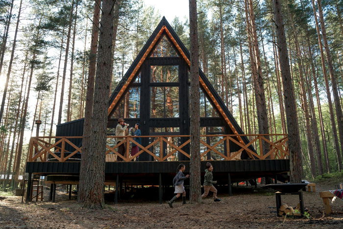 Girl with leukemia watching for bears outside cabin in forest at dusk while her father looks on and children run nearby. Girl with leukemia watching for bears outside cabin in forest at dusk while her father looks on and children run nearby.