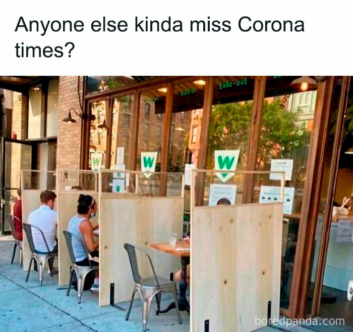 Outdoor cafe with people seated in separate booths, capturing introverts' social struggles during pandemic times.